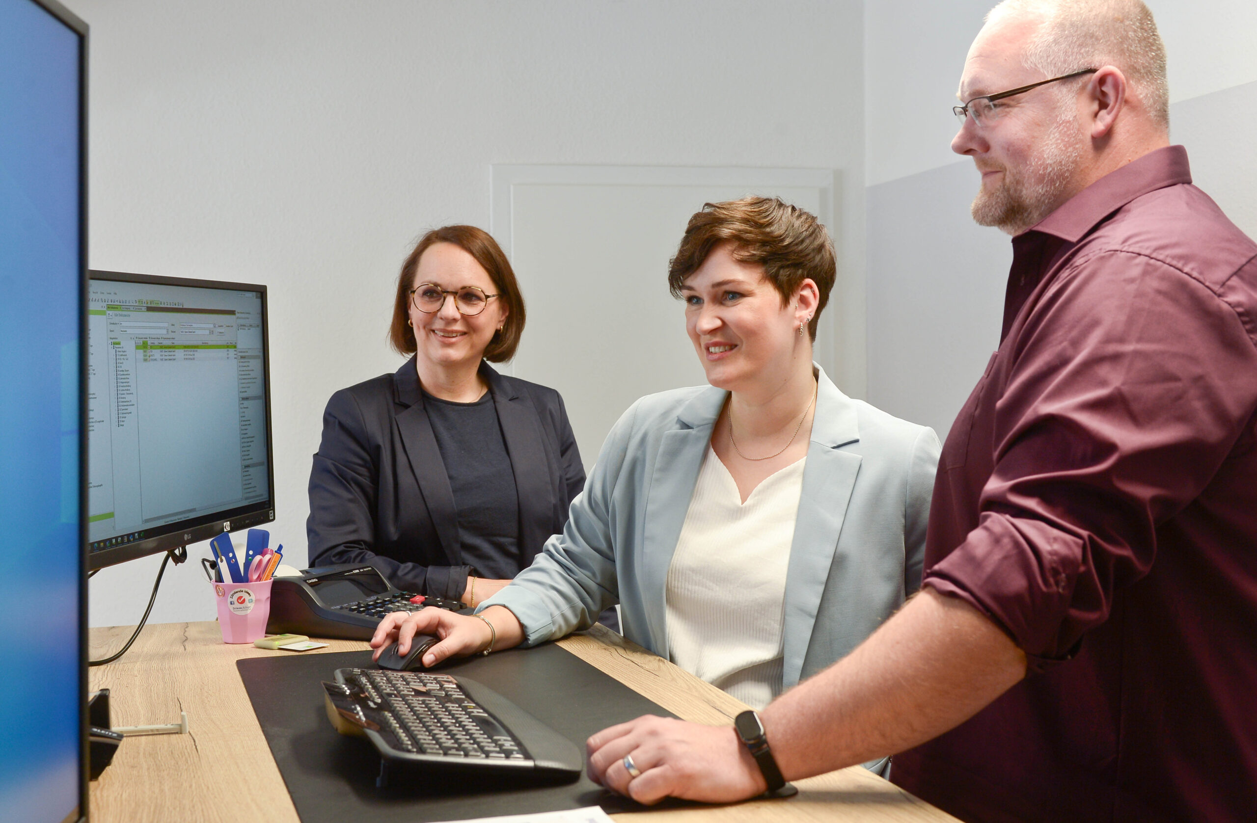 Drei Personen schauen in den Bildschirm am Arbeitsplatz